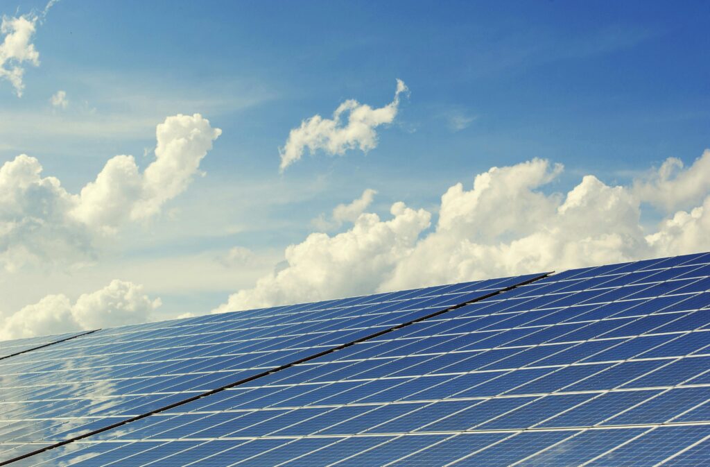 Placas de geração solar no setor de energia refletindo o céu com nuvens brancas